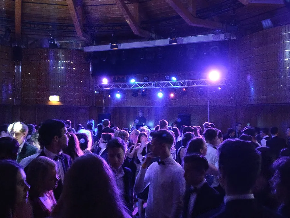 Ballgäste auf der Tanzfläche im Casineum Velden, dahinter DJ unter blauer Lichttraverse