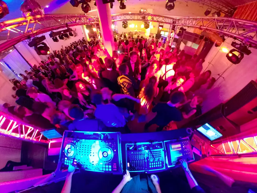 Blick vom DJ-Pult auf die volle, bunt beleuchtete Tanzfläche eines HTL-Balls